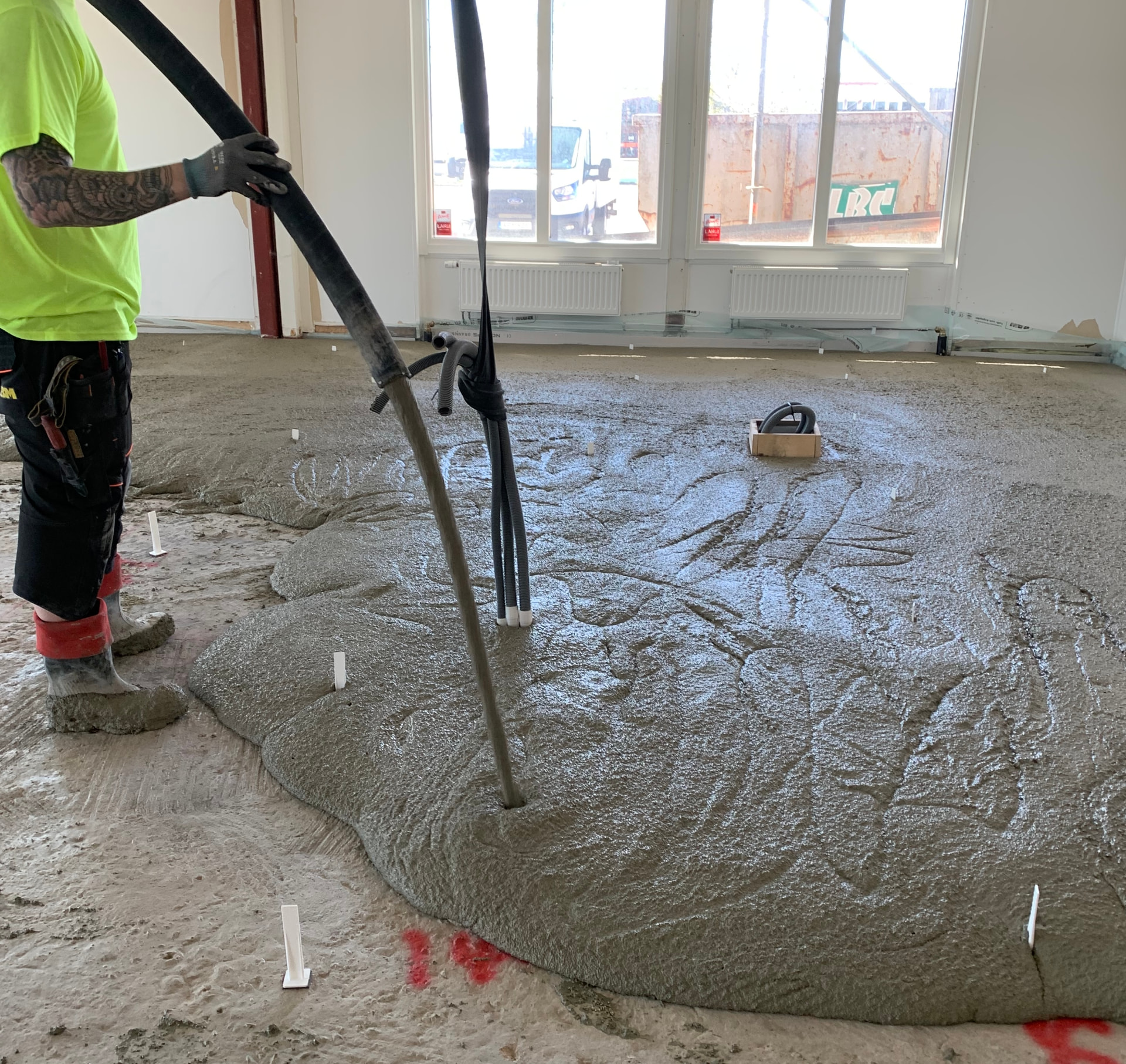 Pumpning av EPS-cement över golvvärmeslingor i en byggnad under uppförande
